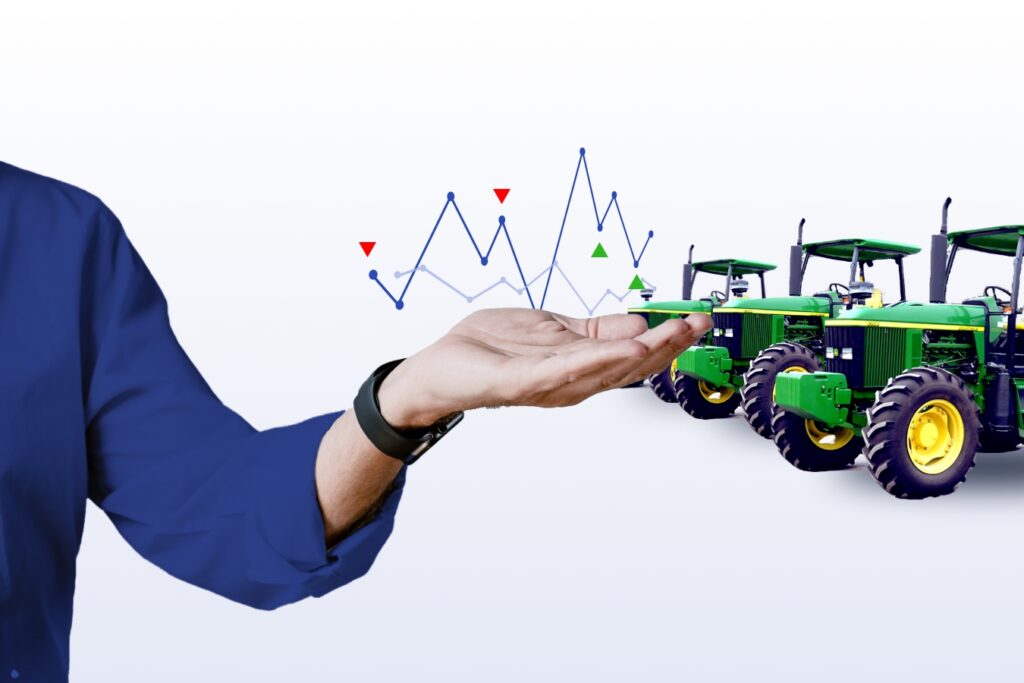 Field technician to the left holding up a line graph with green tractors on the right
