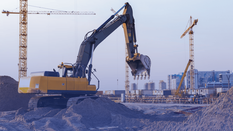 a photo of a construction job site using heavy equipment including cranes and an excavator