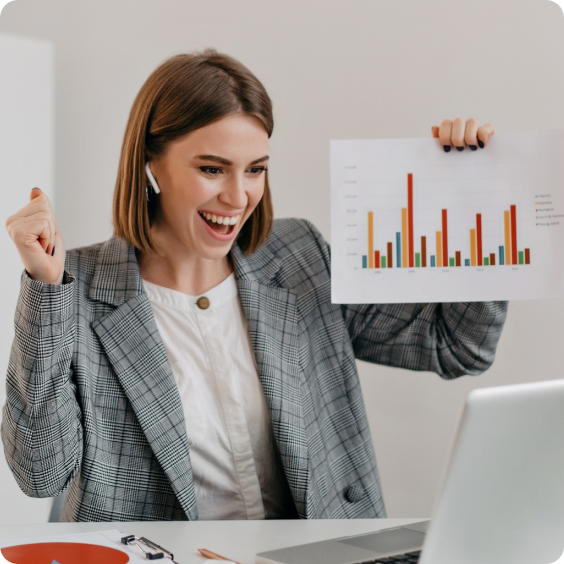 Smiling businesswoman celebrating sales success while holding a bar chart report during a video call