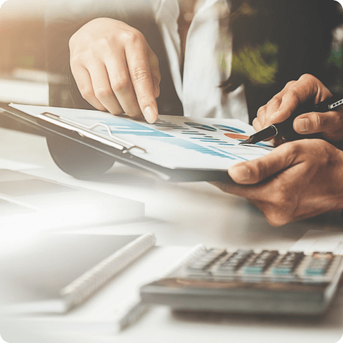 Close-up of business professionals analyzing financial reports with charts, documents, and calculator on desk