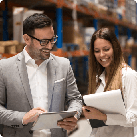 Two professionals discussing vendor management strategies in a warehouse using digital tools
